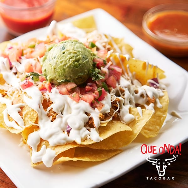 Que Onda Tacobar nachos with ground meat, guacamole, pico de gallo, and sour cream.